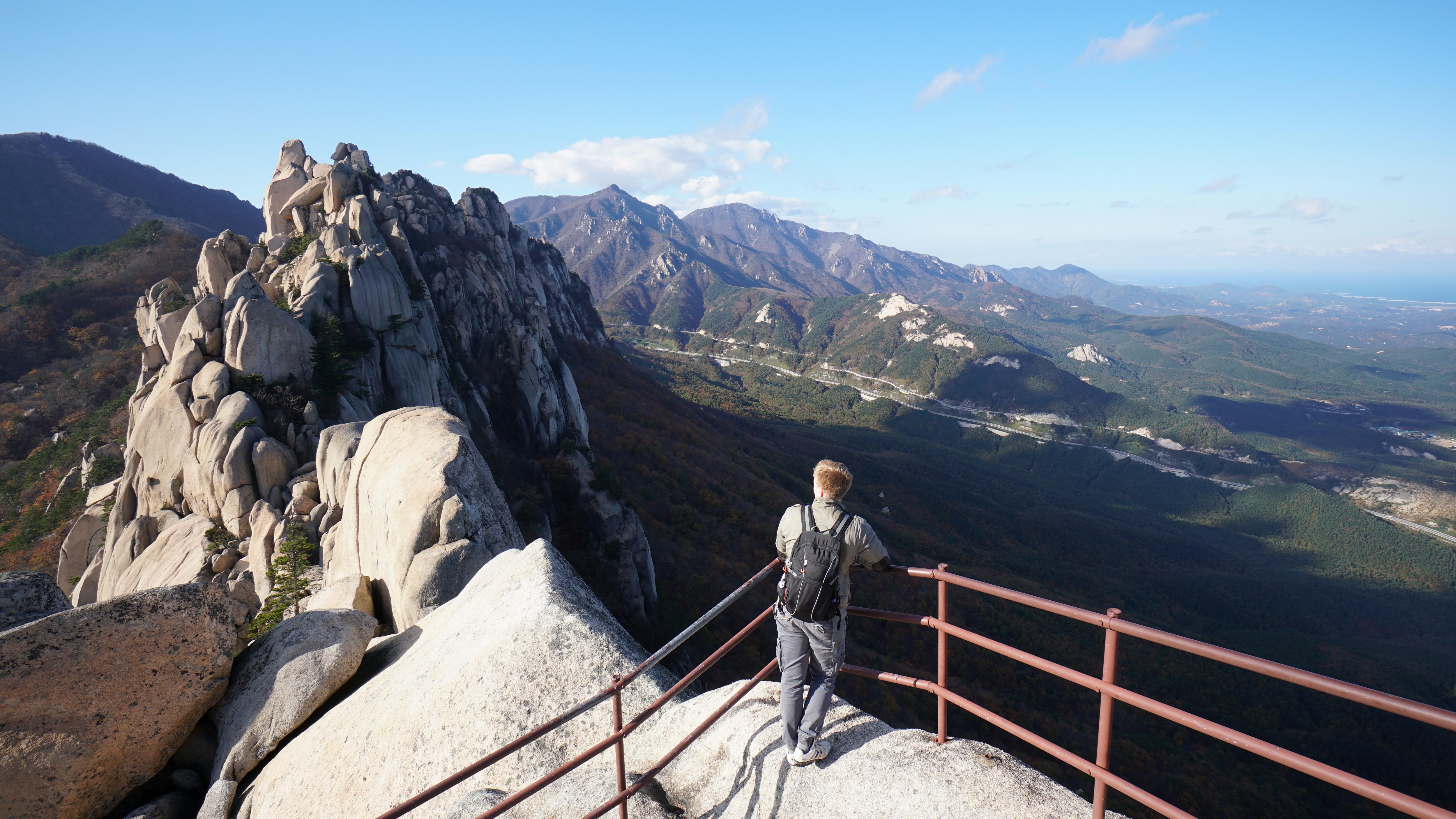 Student hiking with scenic mountain and valley views from a hillside viewpoint