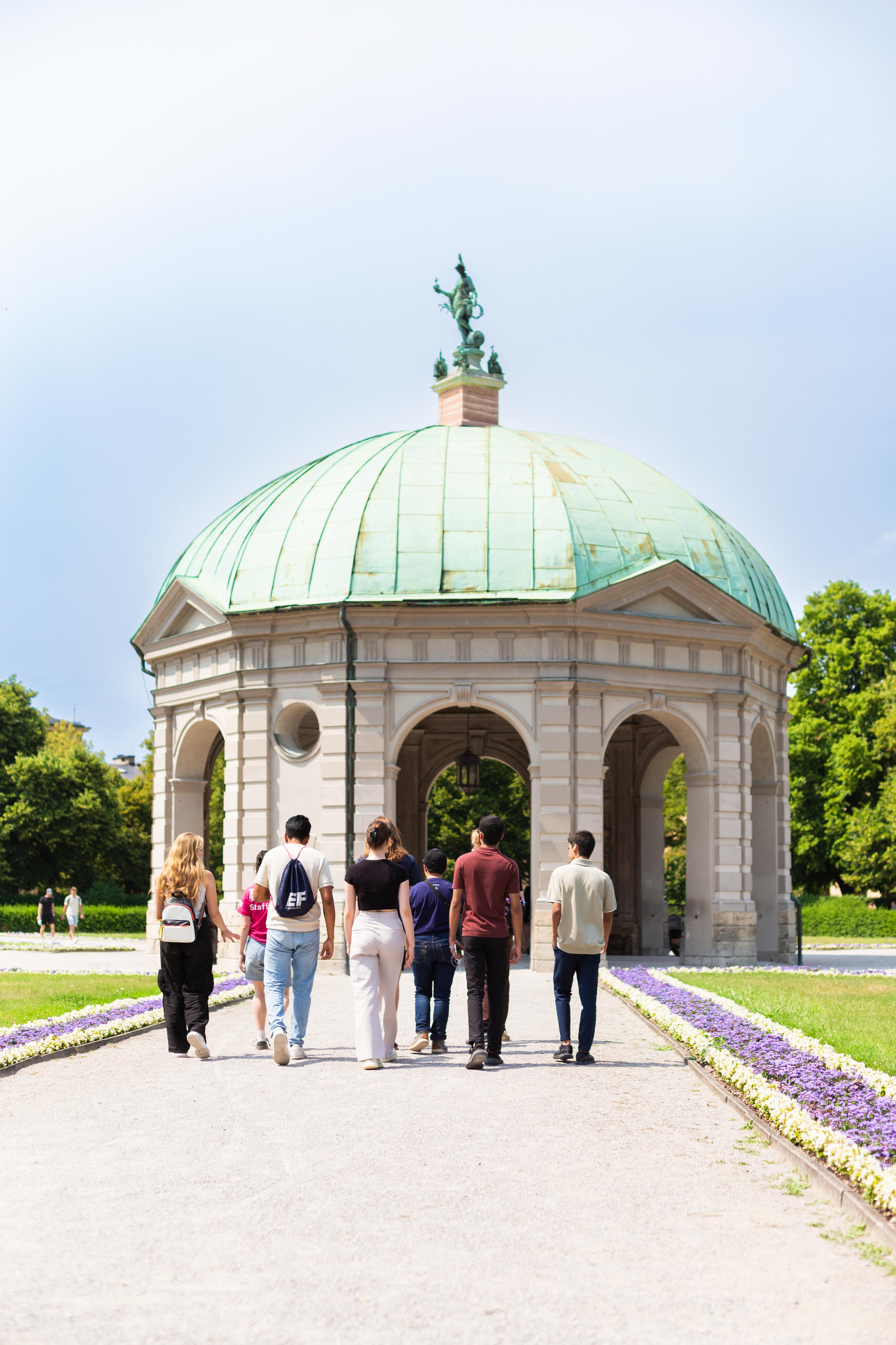 Students walk through a scenic park toward a historic rotunda, enjoying culture, architecture, and the outdoors
