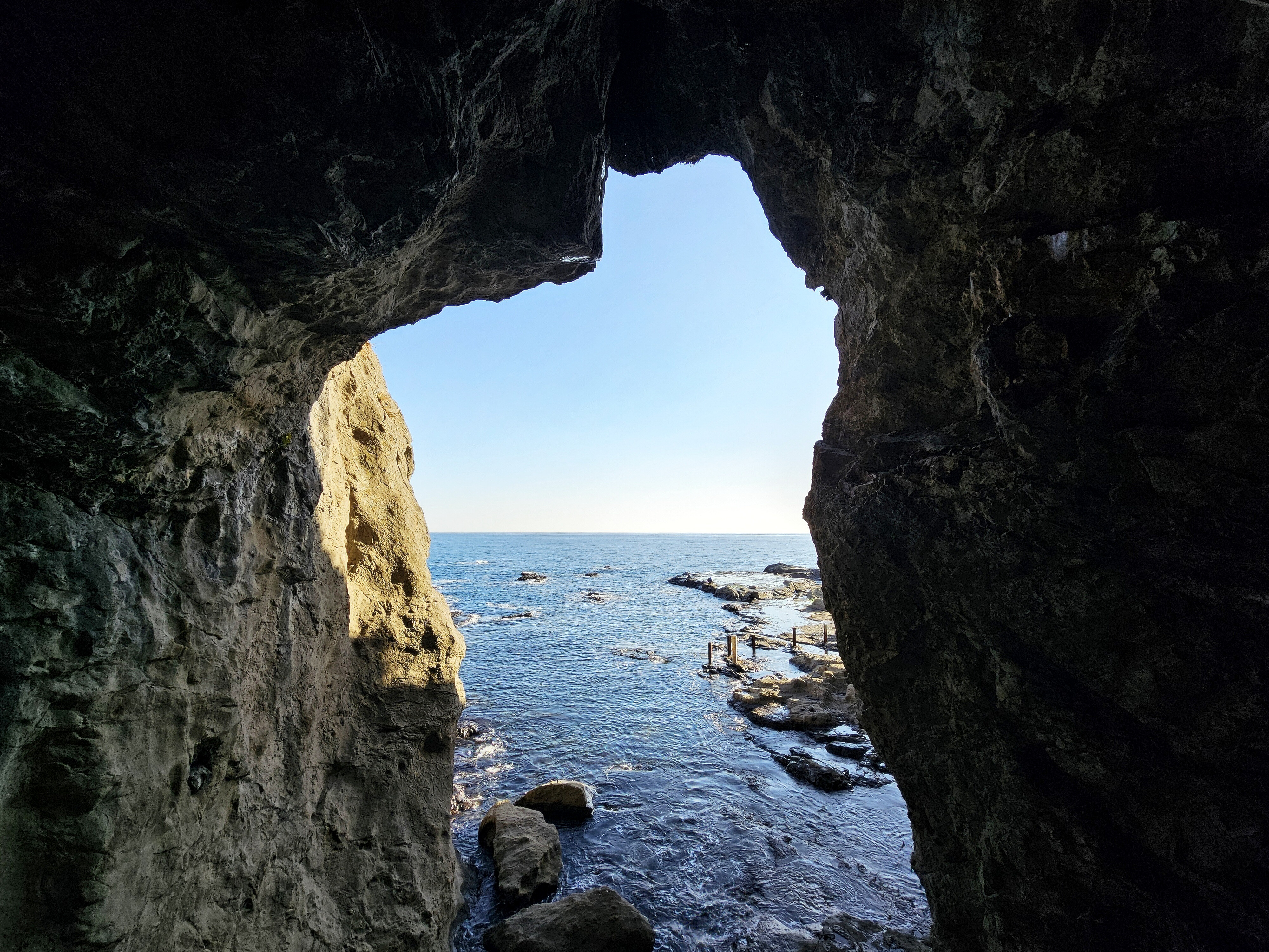 Rock Overhang Framing Serene Blue Sea on a Sunny Coast