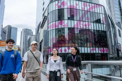 EF Language Abroad students walking together through Shibuya in Tokyo, surrounded by modern glass buildings and city streets.
