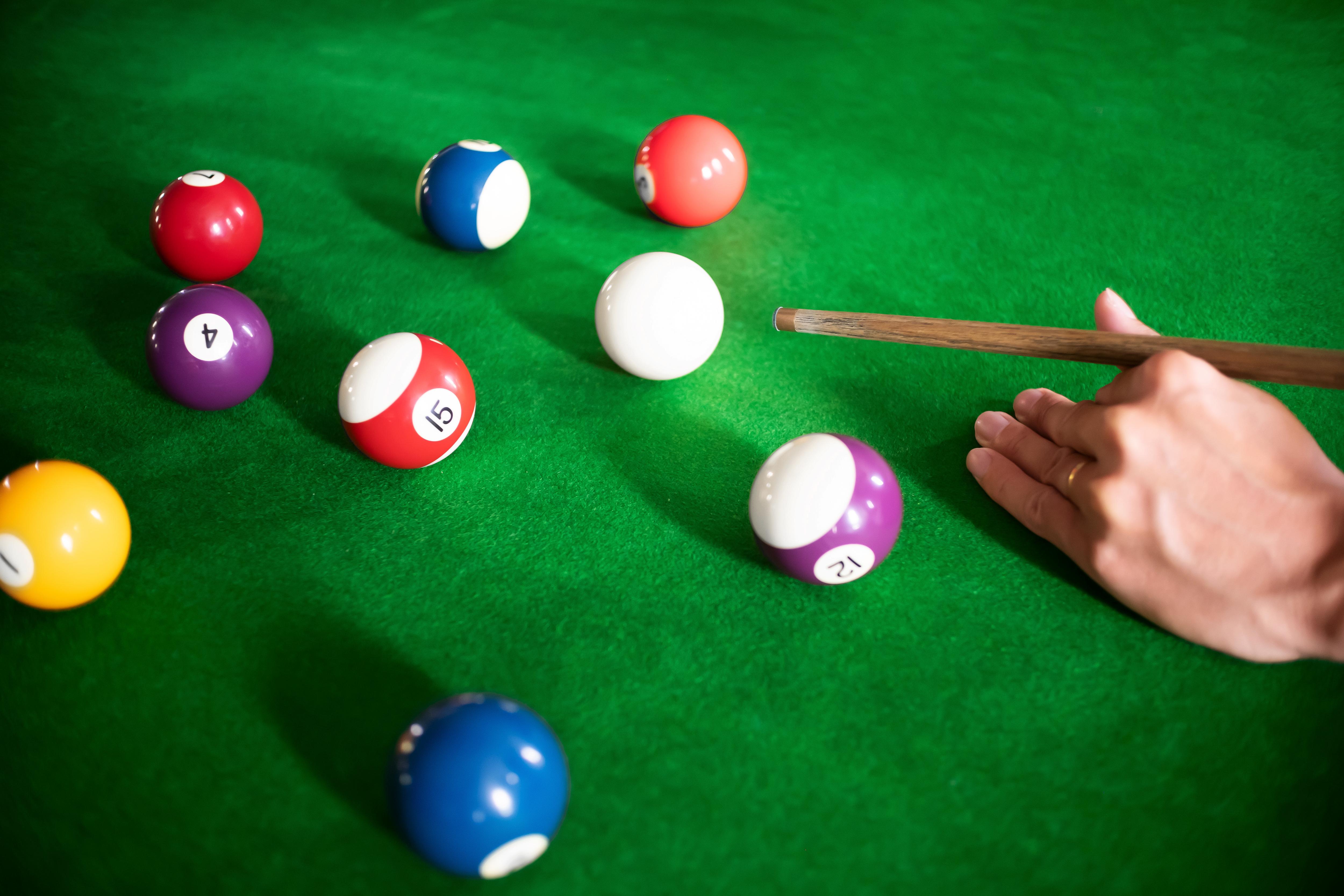 Student lines up a pool shot on a billiards table, enjoying a recreational activity in a social setting