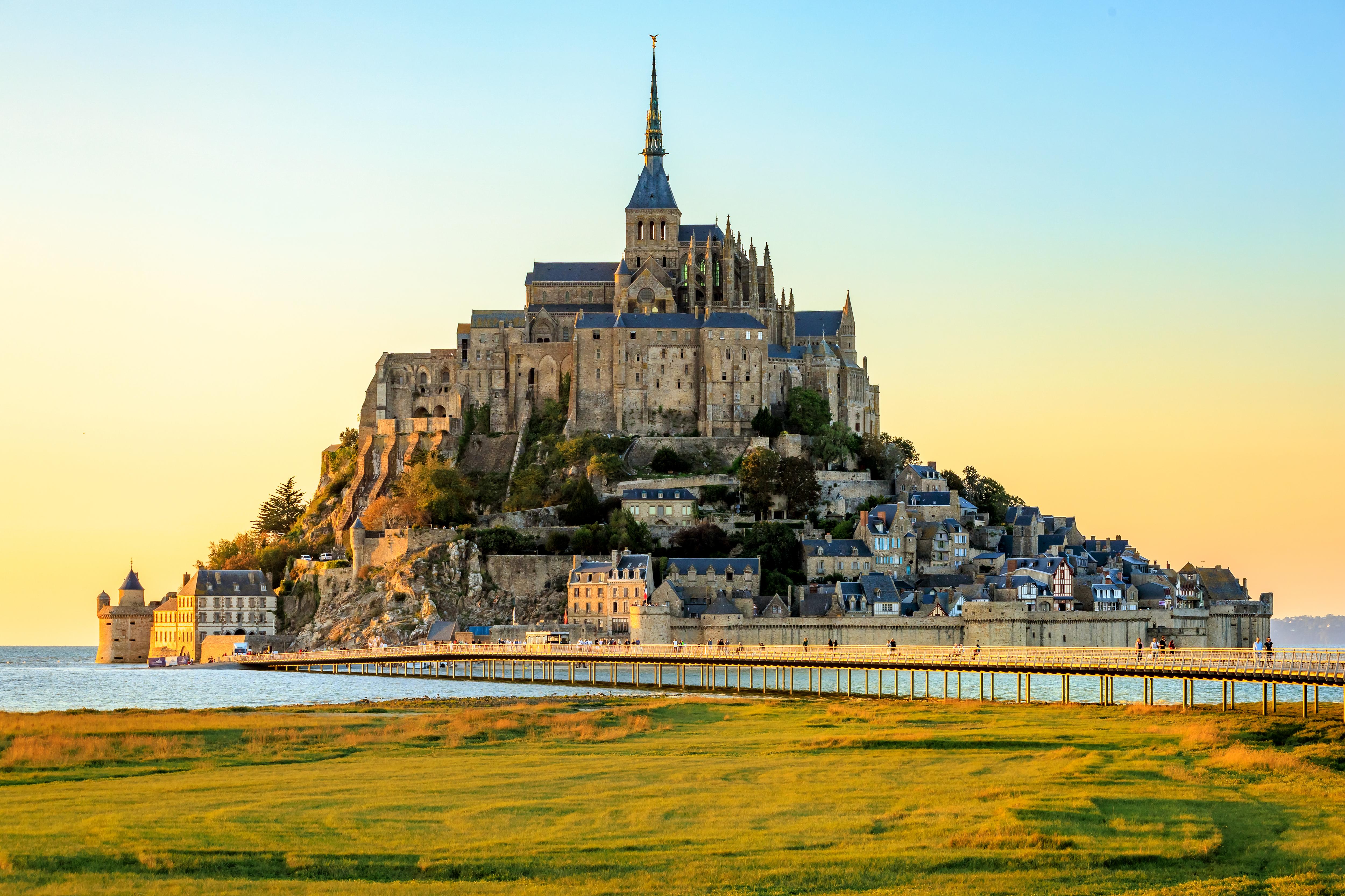 Mont Saint-Michel castle silhouetted against a stunning sunset over the bay