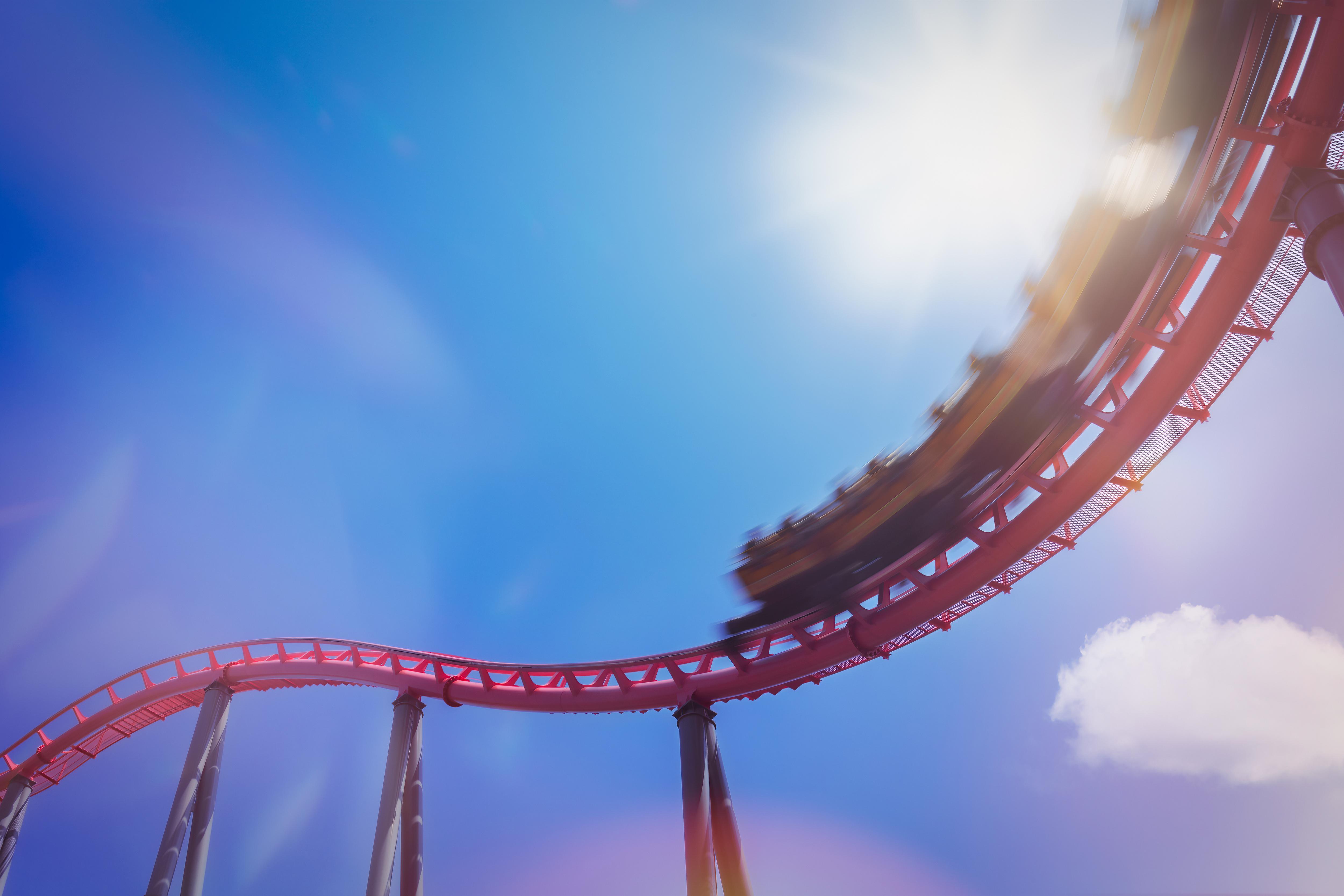 Sunlit Roller Coaster Ride Racing Beneath a Clear Blue Sky