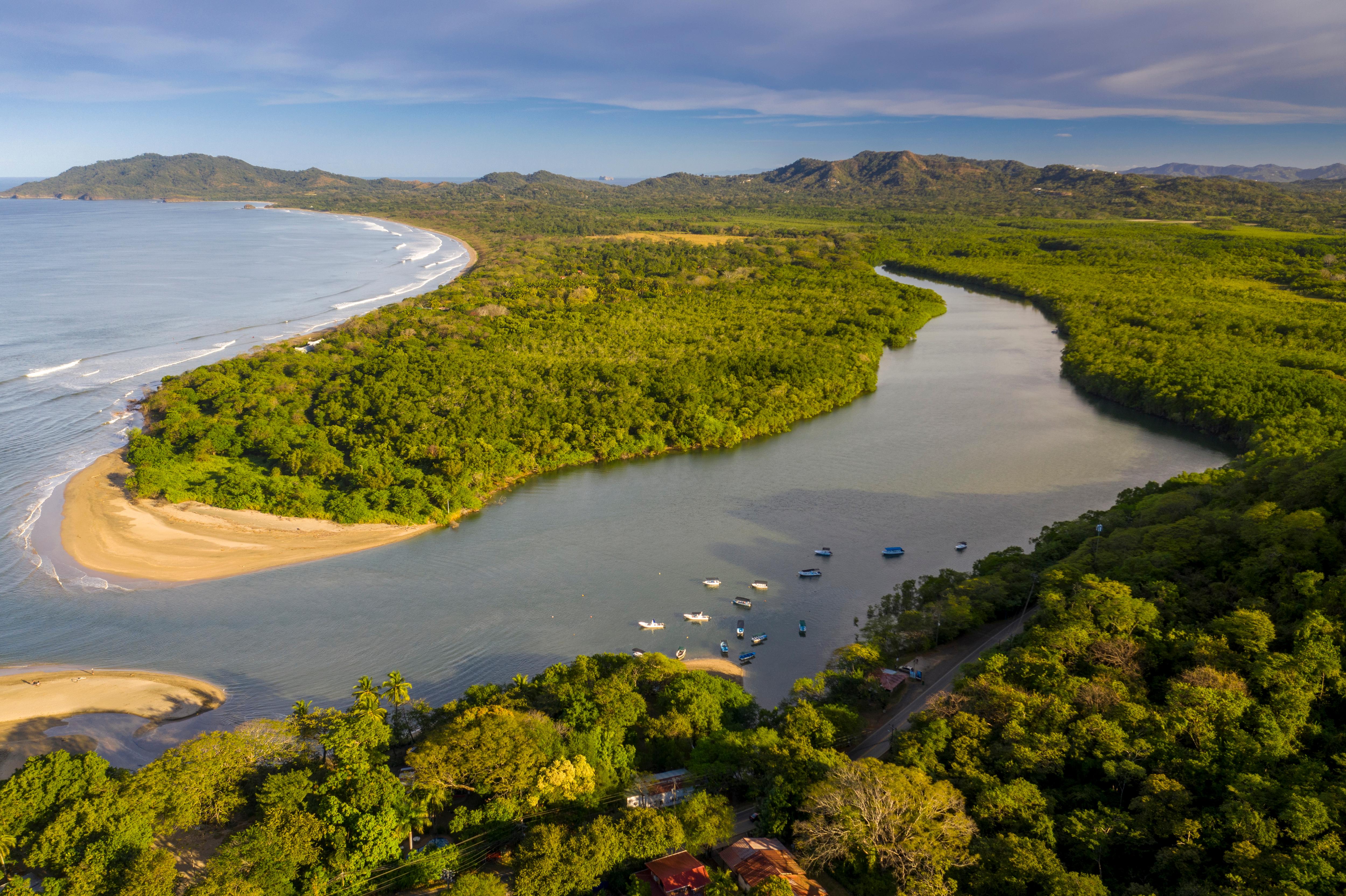 Aerial view of a river meeting the ocean along a scenic coastline