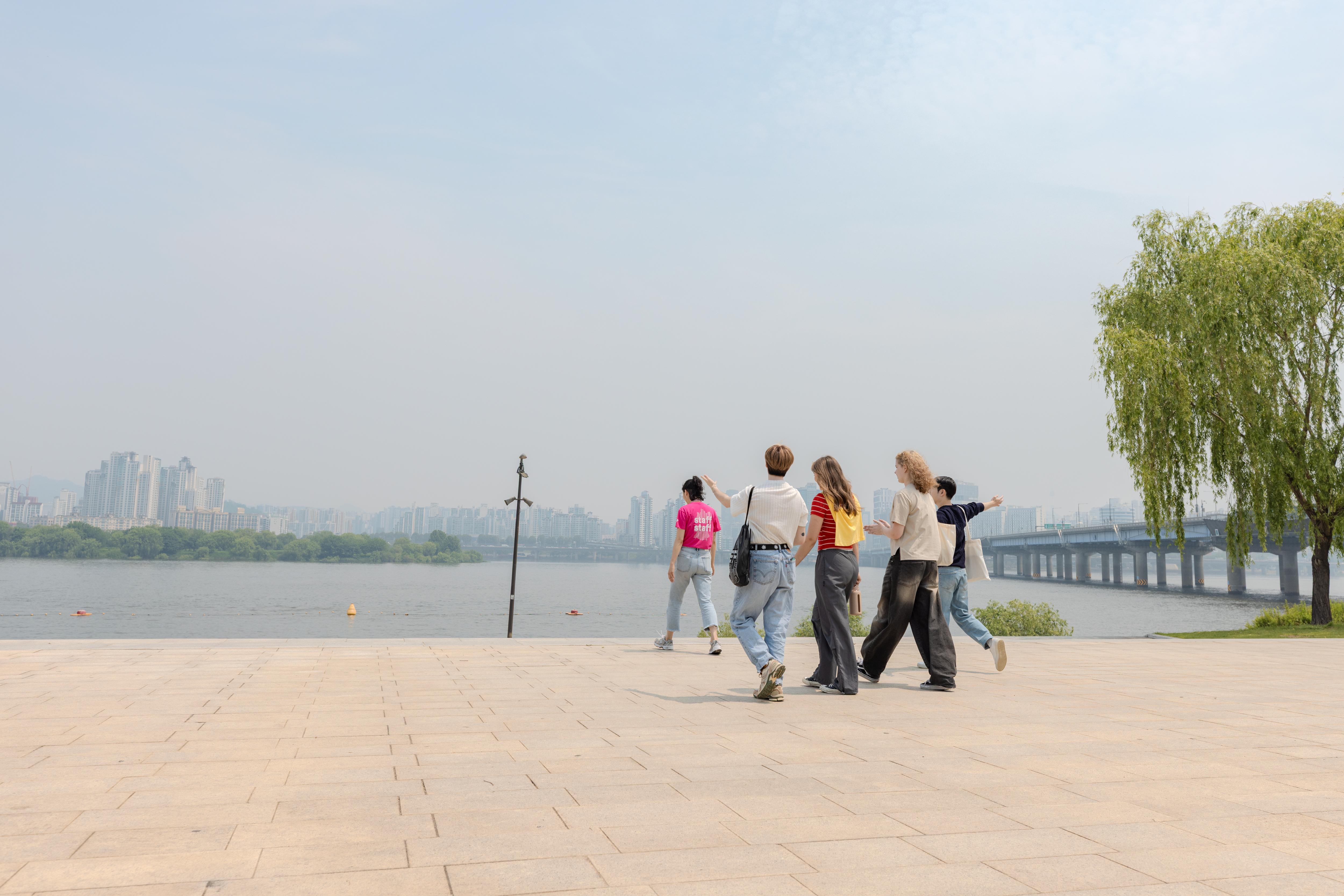 Staff and students on a city excursion, walking along a riverside promenade