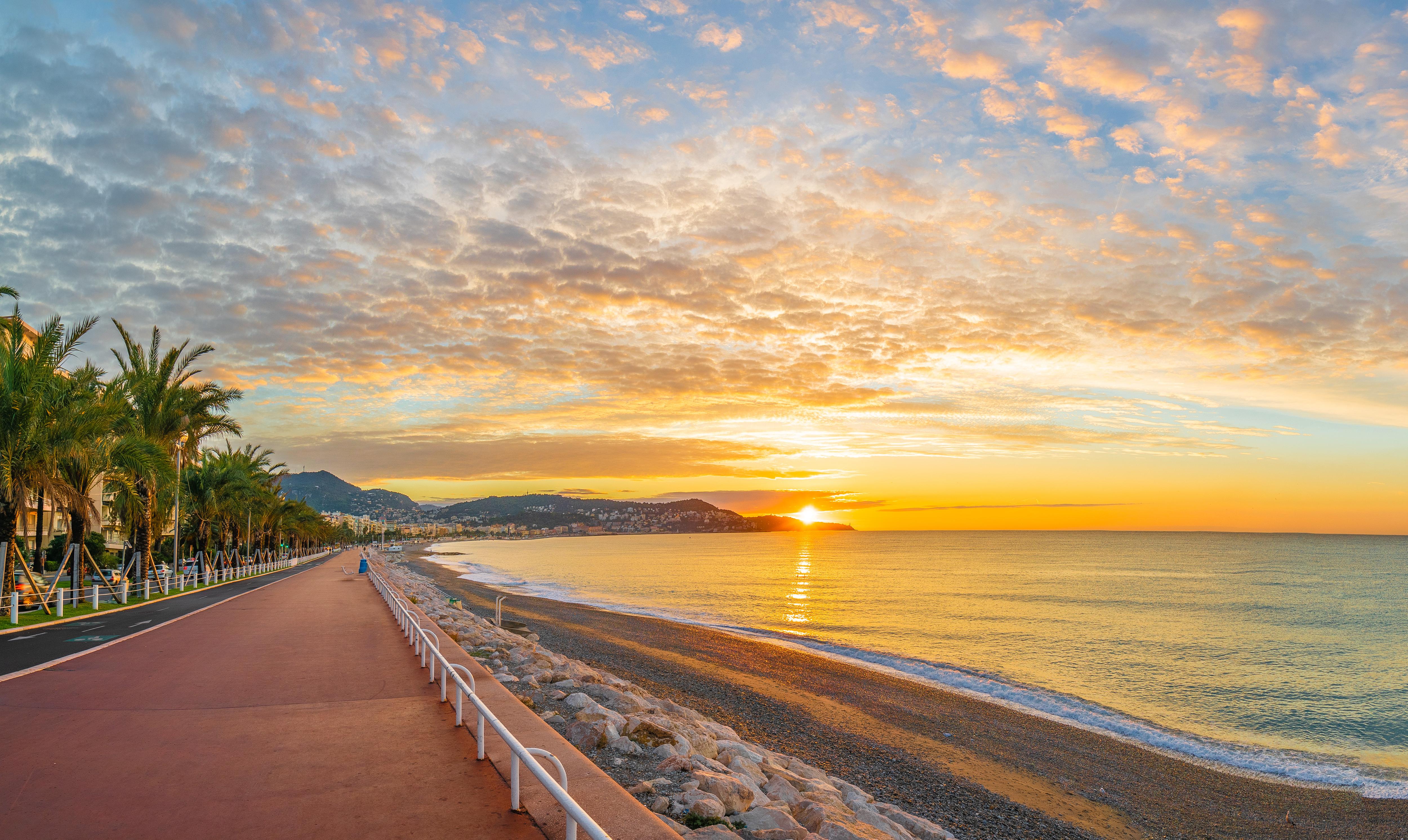 Peaceful sunrise by the sea, taking in scenic coastal views along a palm-lined promenade