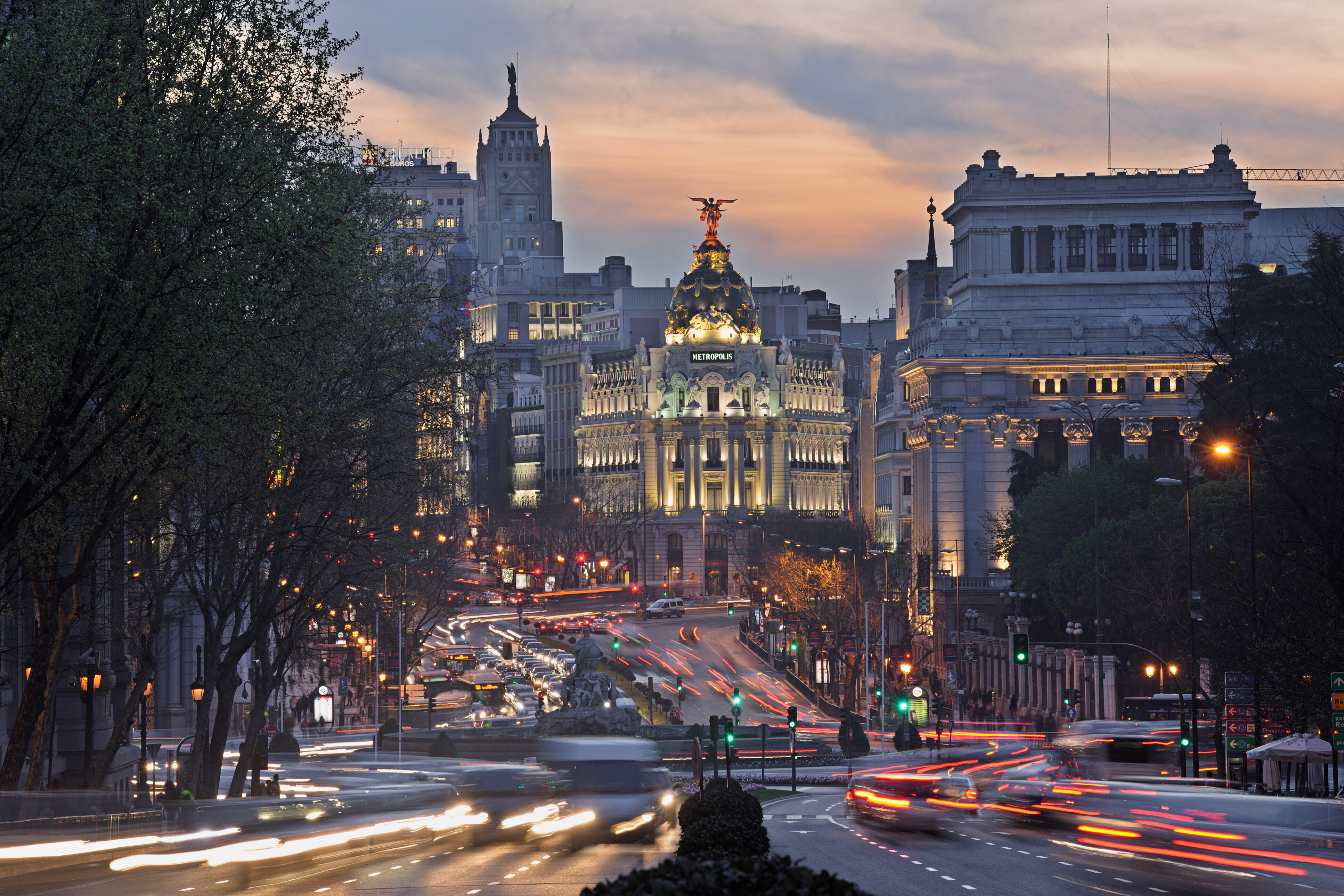 Madrid’s bustling boulevard at sunset, featuring the iconic Metropolis Building