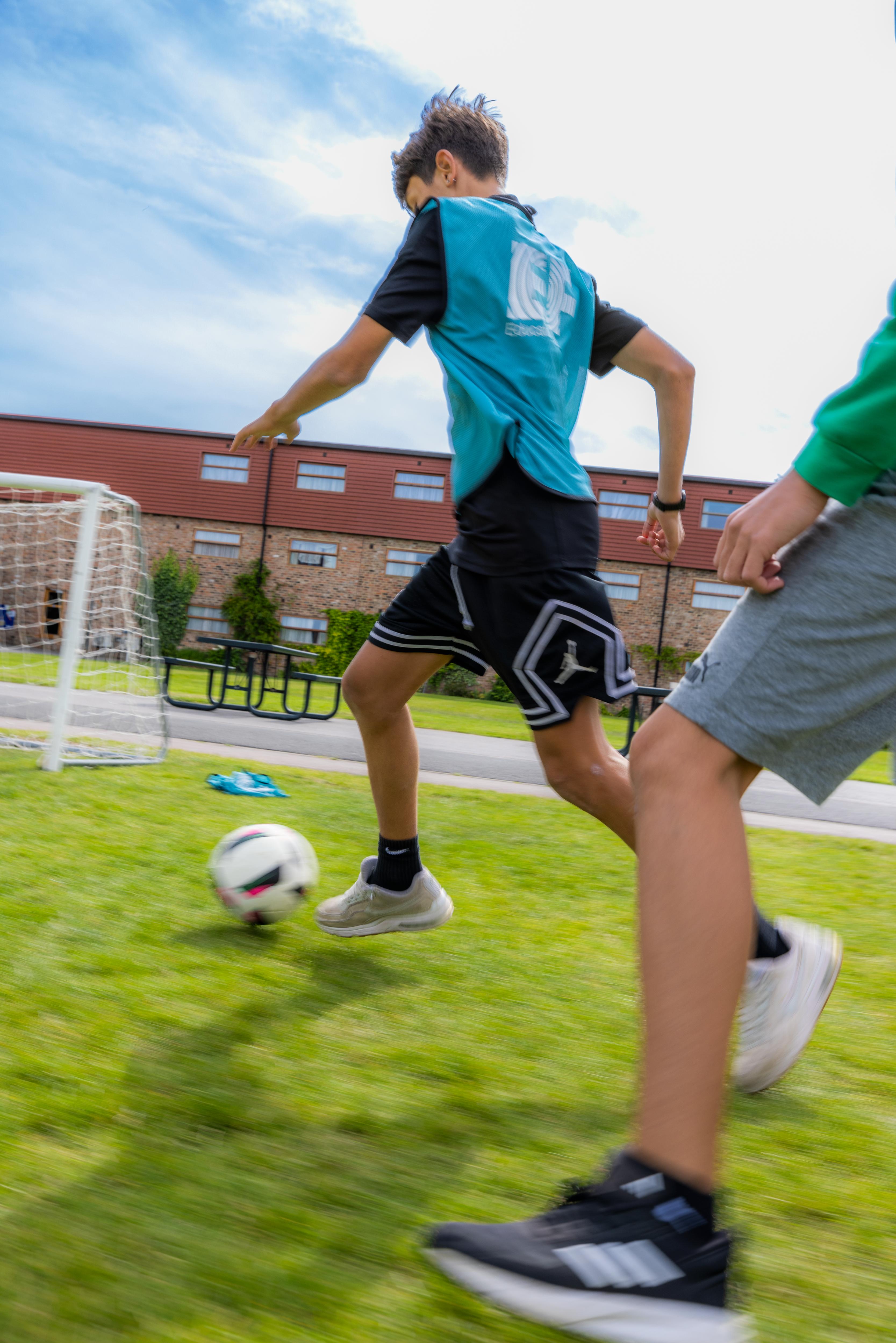 Two students play soccer on a grass field, enjoying an active and engaging outdoor sports activity