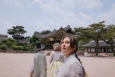 EF Language Abroad students exploring a traditional palace in Seoul, wearing hanbok and walking through historic courtyards surrounded by ornate wooden buildings and pine trees.