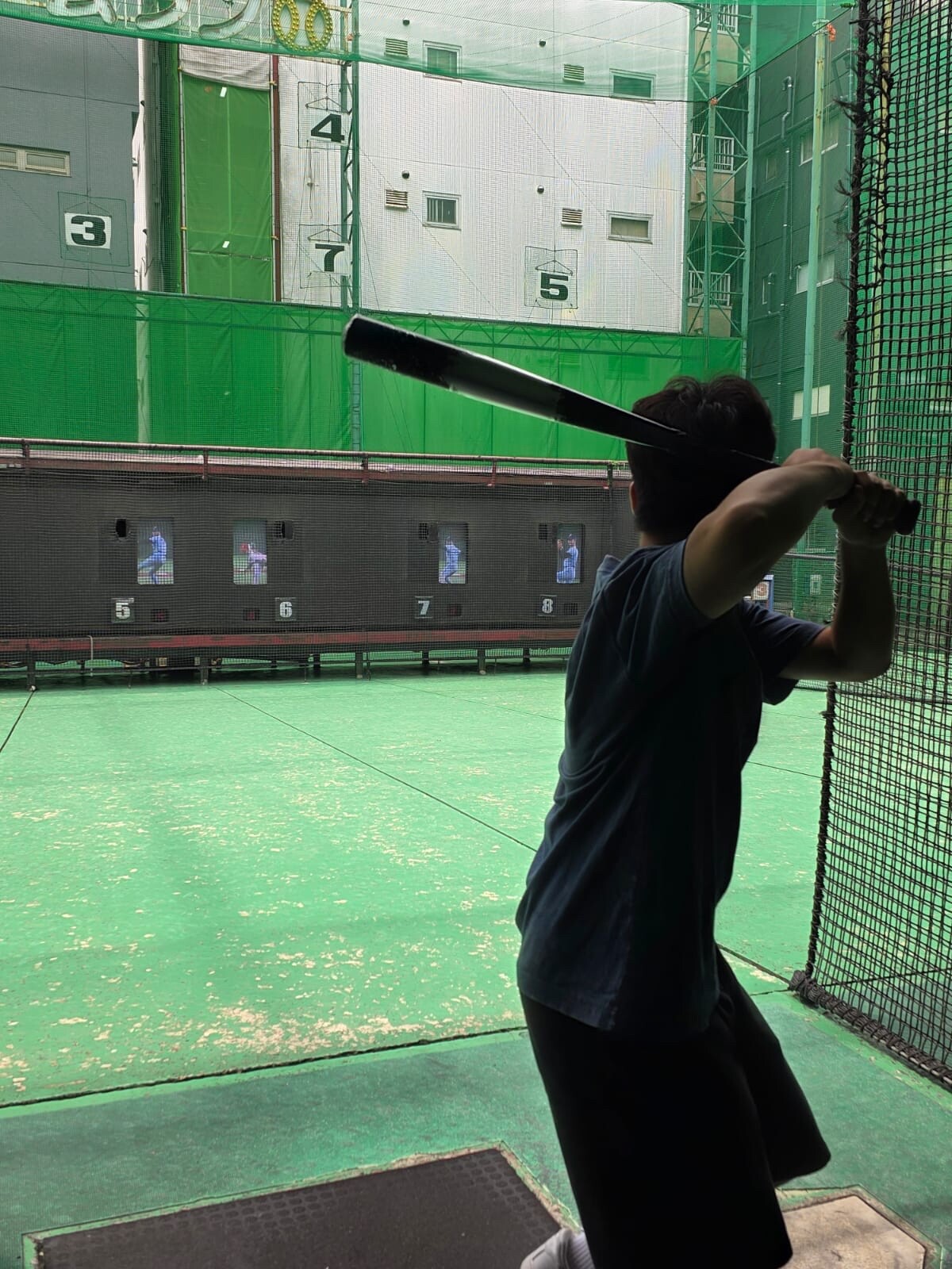 Student practices baseball in an indoor batting cage, taking part in an active sports training session
