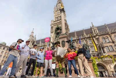 EF Language Abroad students gathered in Marienplatz in Munich, listening to a street musician playing the accordion in front of the historic Neues Rathaus.