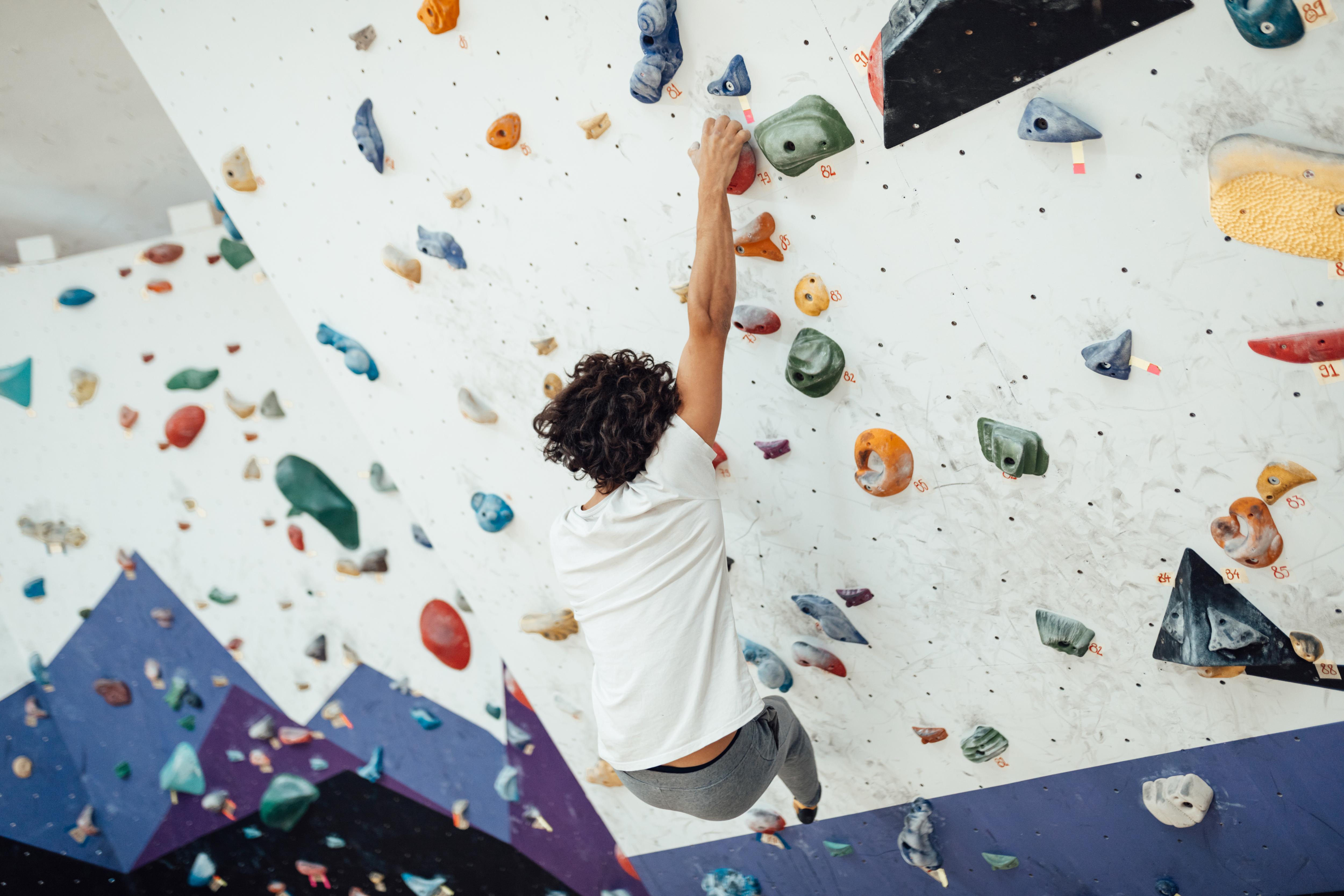 Student climbs an indoor rock wall, challenging themselves through an active and engaging fitness activity
