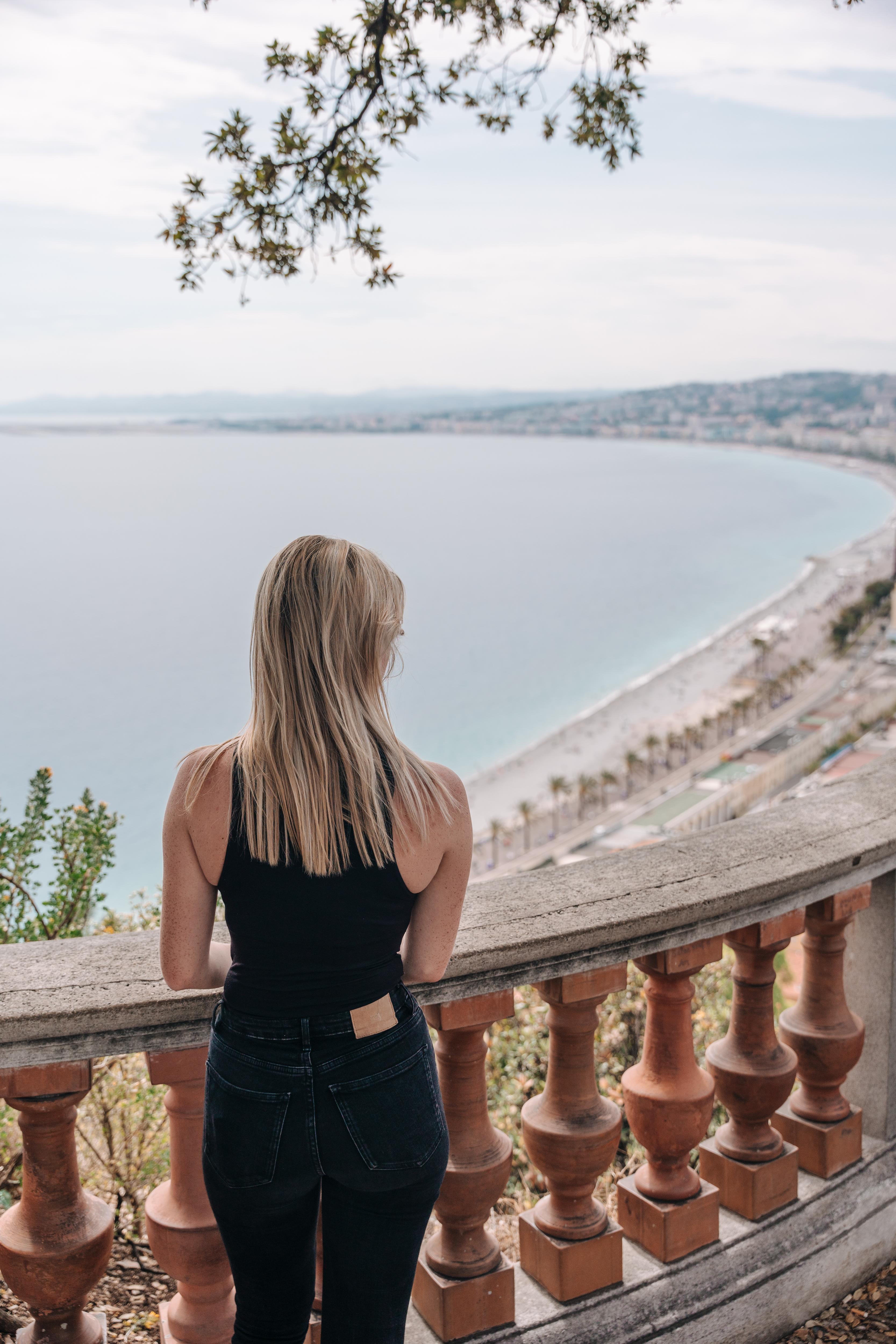 Student enjoys a coastal city view from a balcony, taking in scenic beach and ocean surroundings