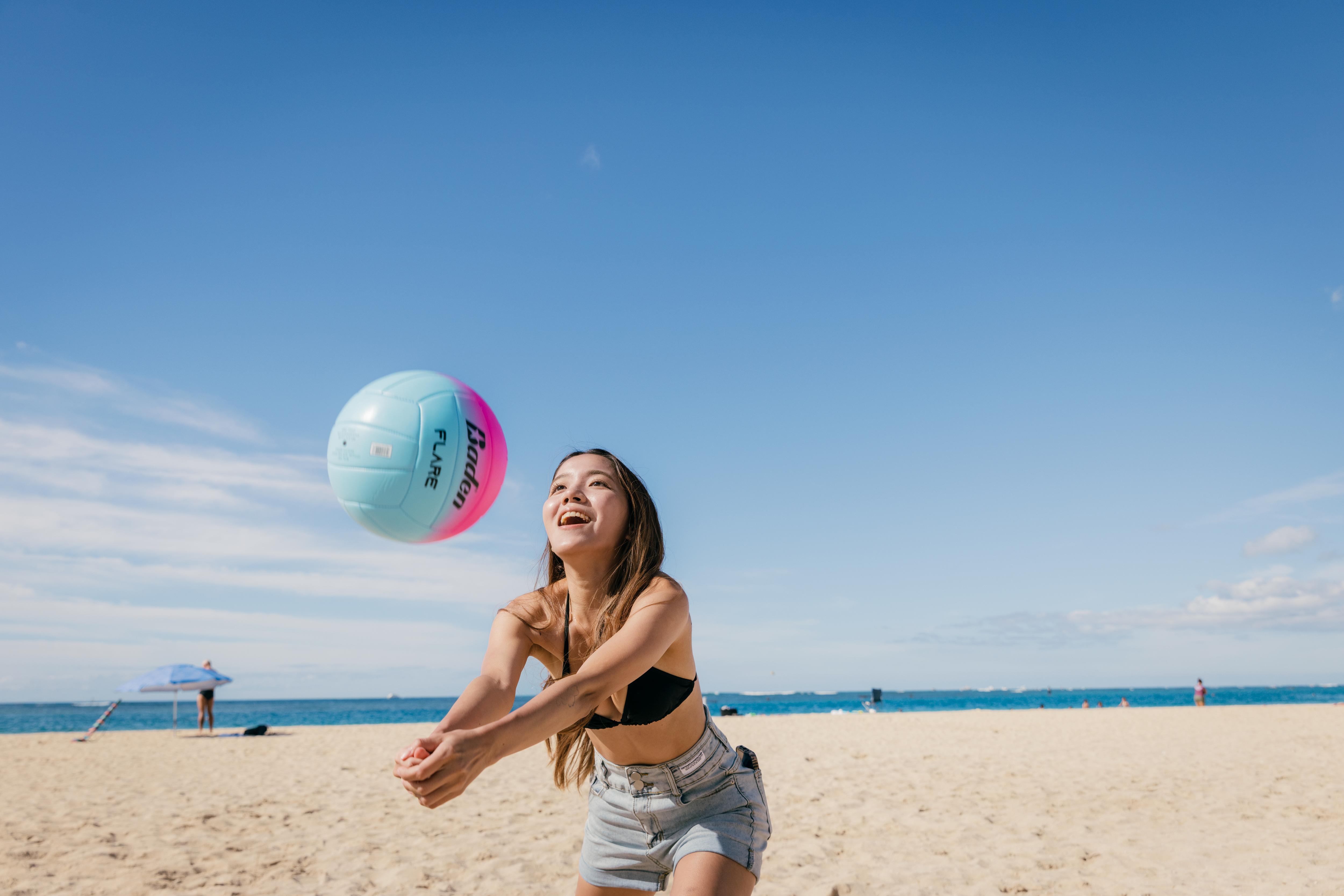 Student plays beach volleyball by the ocean, enjoying an active and engaging outdoor sports activity