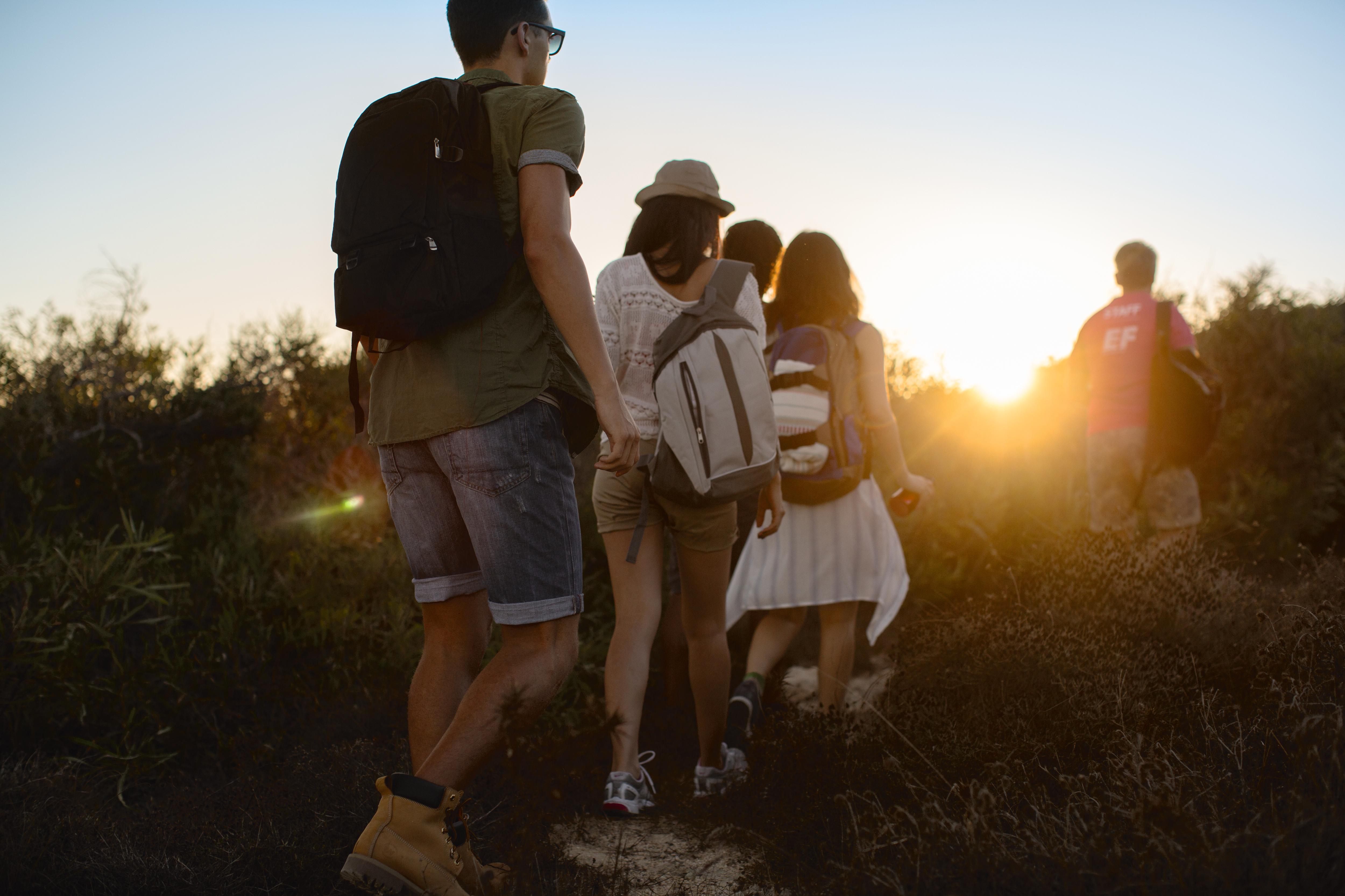 Students hiking at sunset through a forest trail