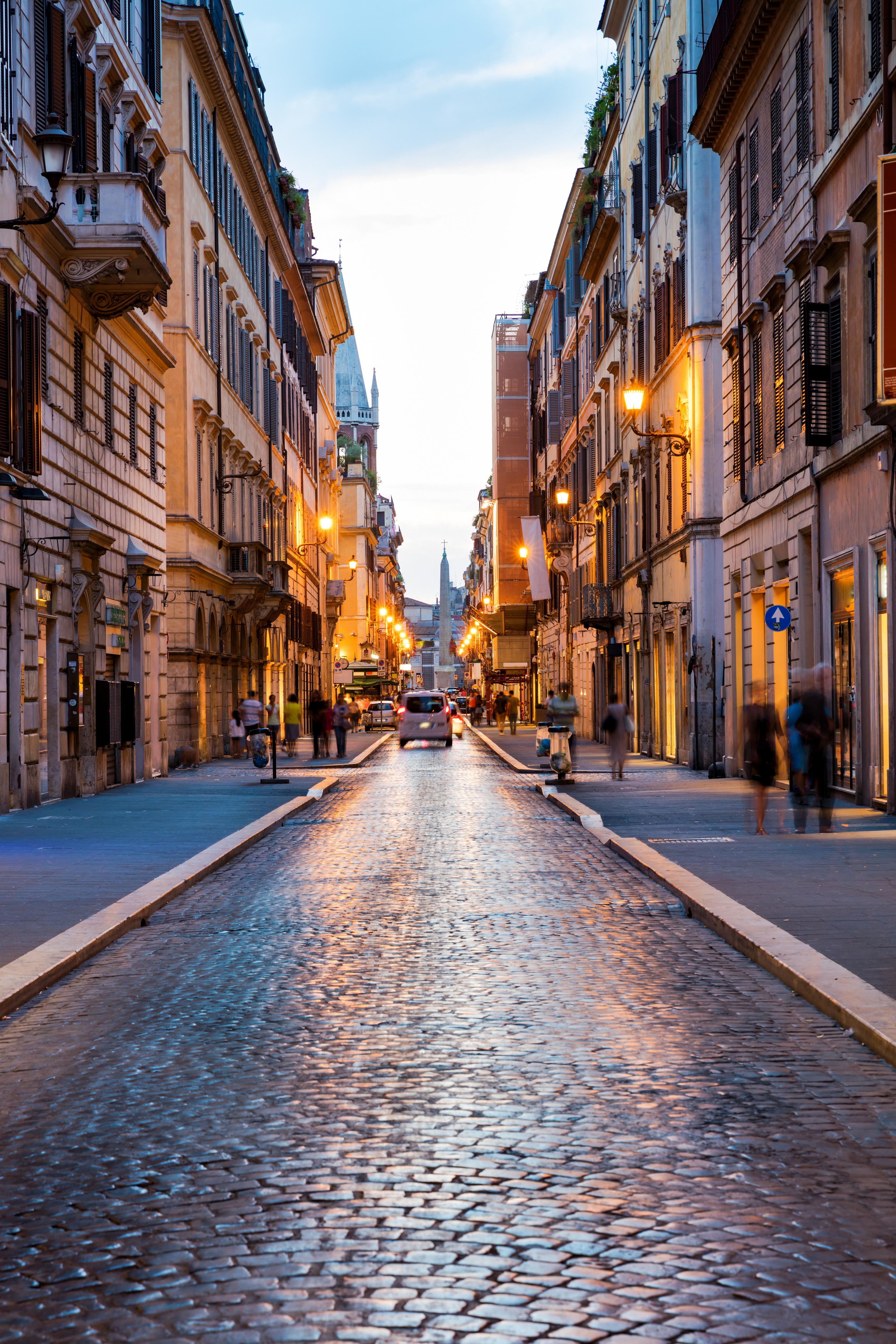 Cobblestone street in a European city, lined with tall buildings featuring shops and residences