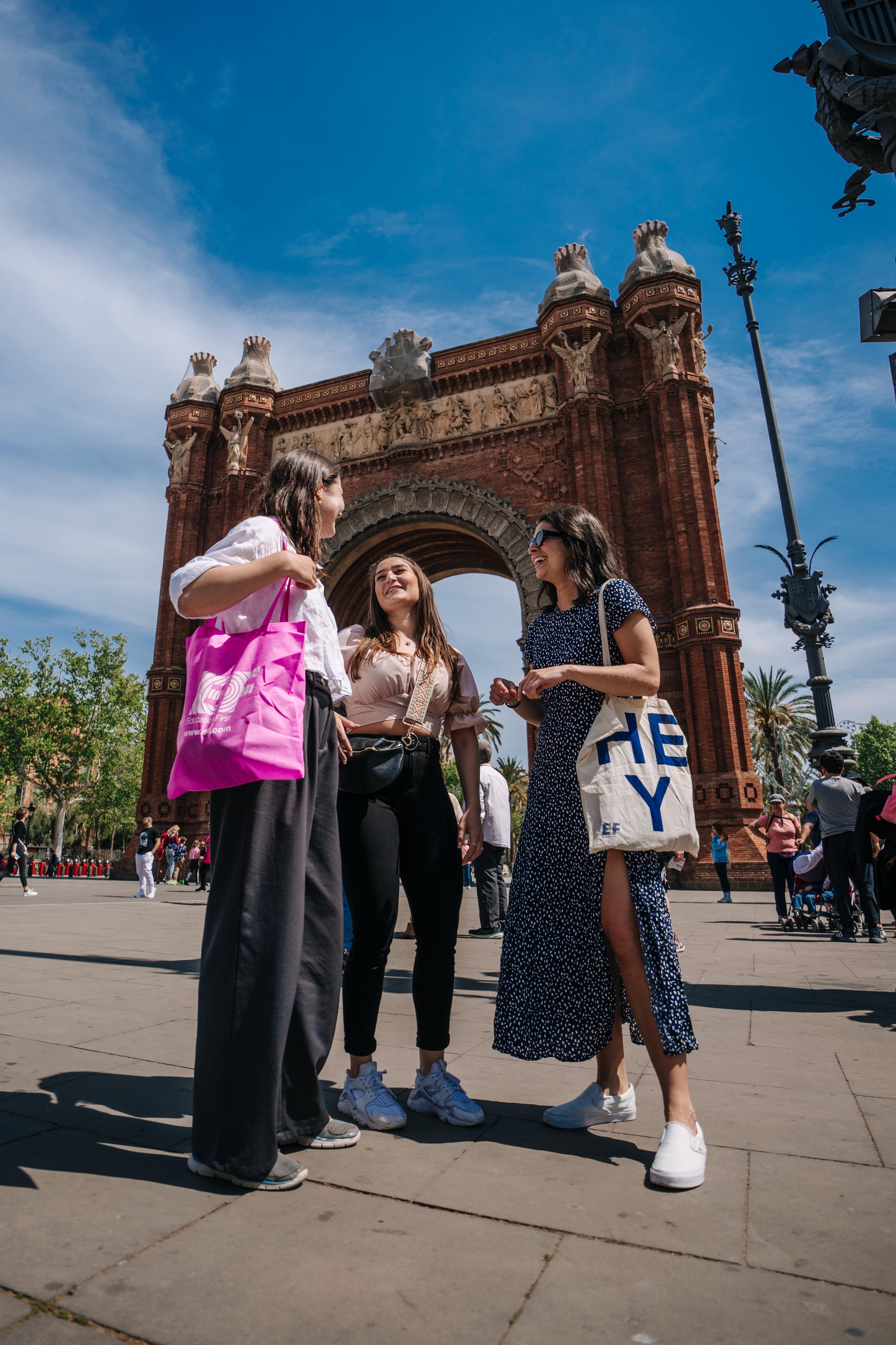 Three students chat in front of Barcelona’s Arc de Triomf, enjoying a sunny day and cultural sightseeing