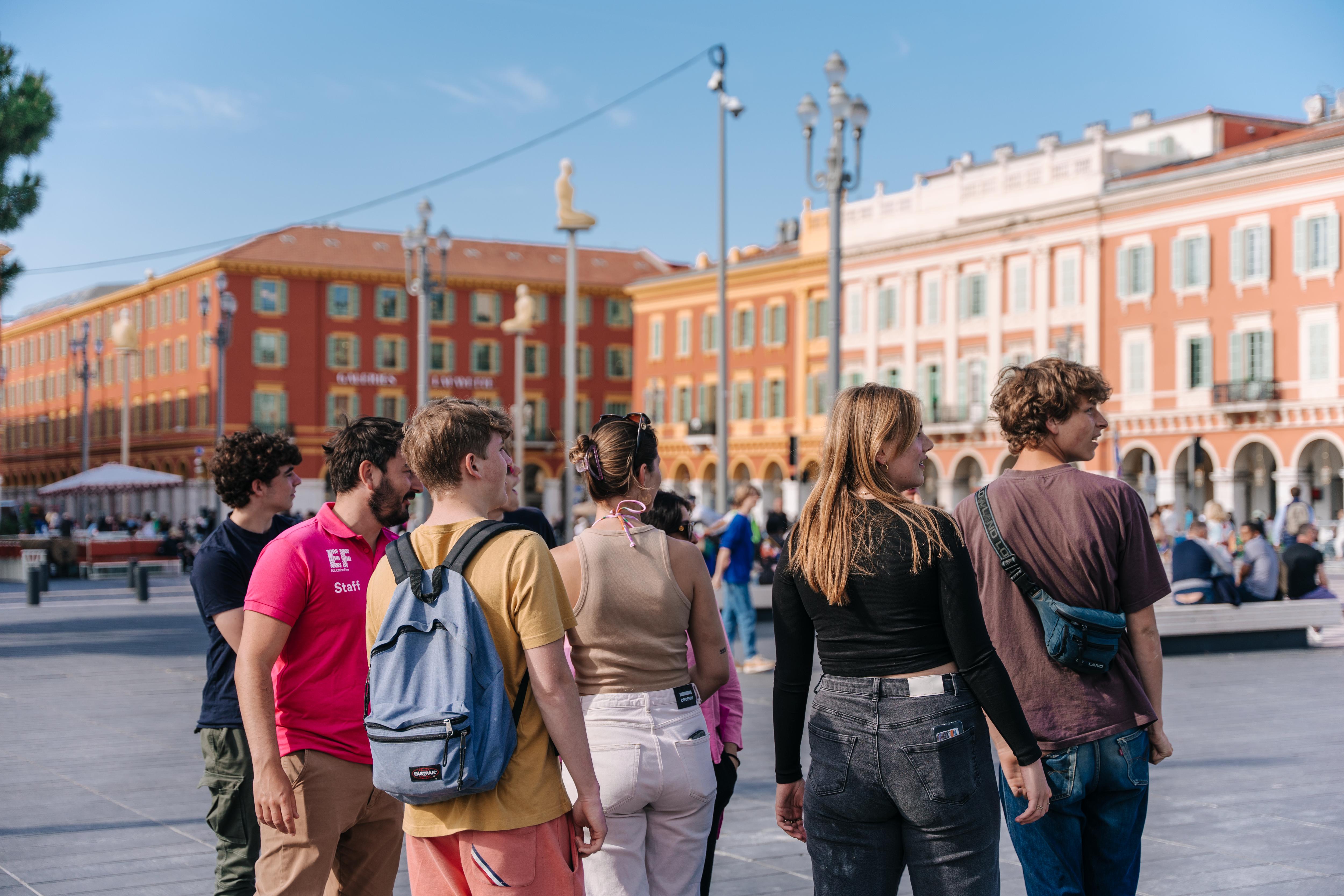 Students gather in a sunny European square, exploring local culture and historic architecture during a guided city experience