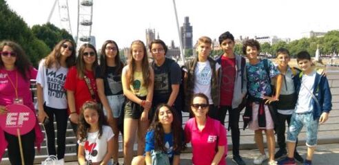 A group of students poses for a photo in front of the London Eye and the Houses of Parliament.