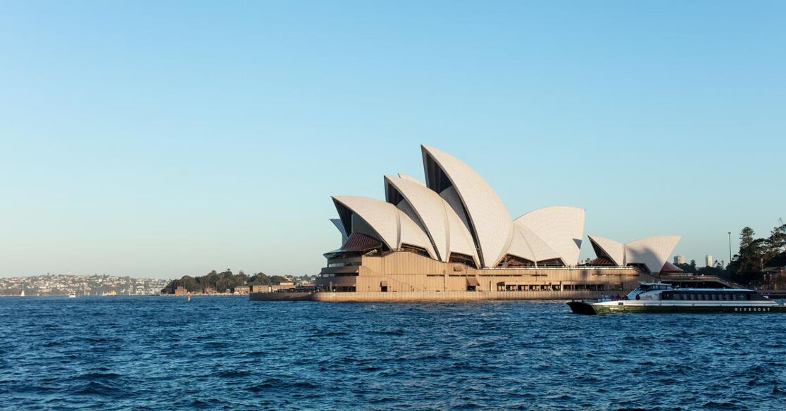 The image displays the Sydney Opera House in Australia, an iconic landmark renowned for its distinctive sail-like architecture, situated on the harbor's edge.