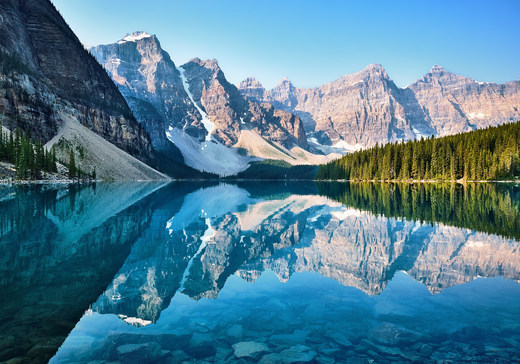 A breathtaking view of Moraine Lake in Banff National Park, Canada, showcasing its turquoise waters and the majestic snow-capped peaks of the Ten Peaks reflected in the calm water.