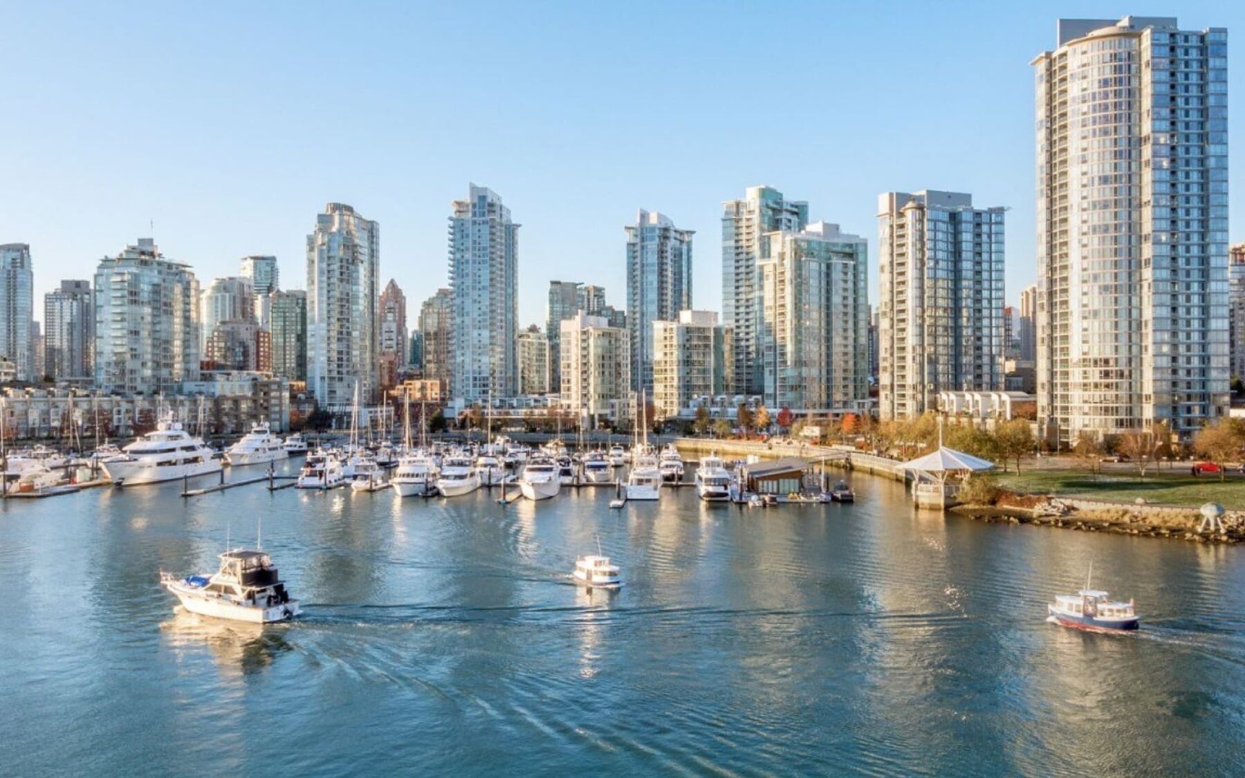 A picturesque view of the Vancouver skyline, featuring a bustling marina in the foreground, reflecting the cityscape with its towering buildings and tranquil waters.