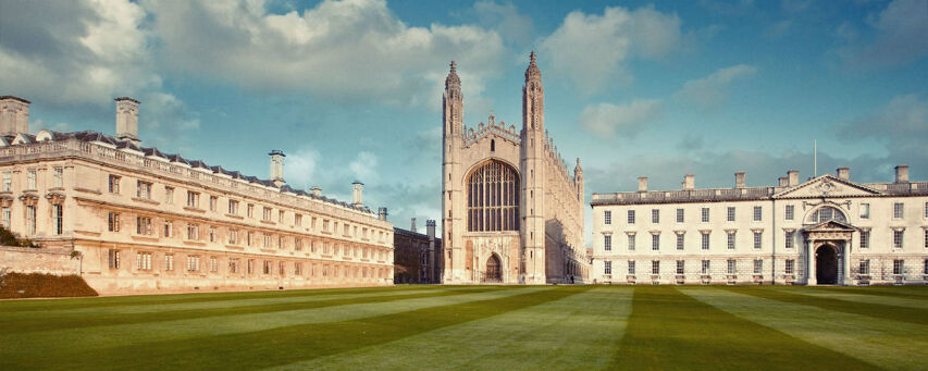 This is a wide-angle shot of King's College Chapel in Cambridge, England, with its iconic fan vaulting visible. The image showcases the stunning architecture and the meticulously maintained grounds.