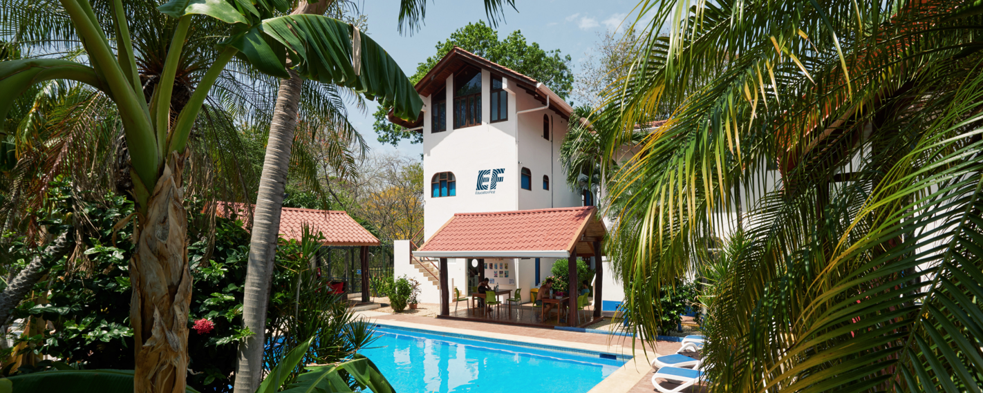A sunny day in a tropical setting featuring an EF building, a swimming pool, and lush greenery.