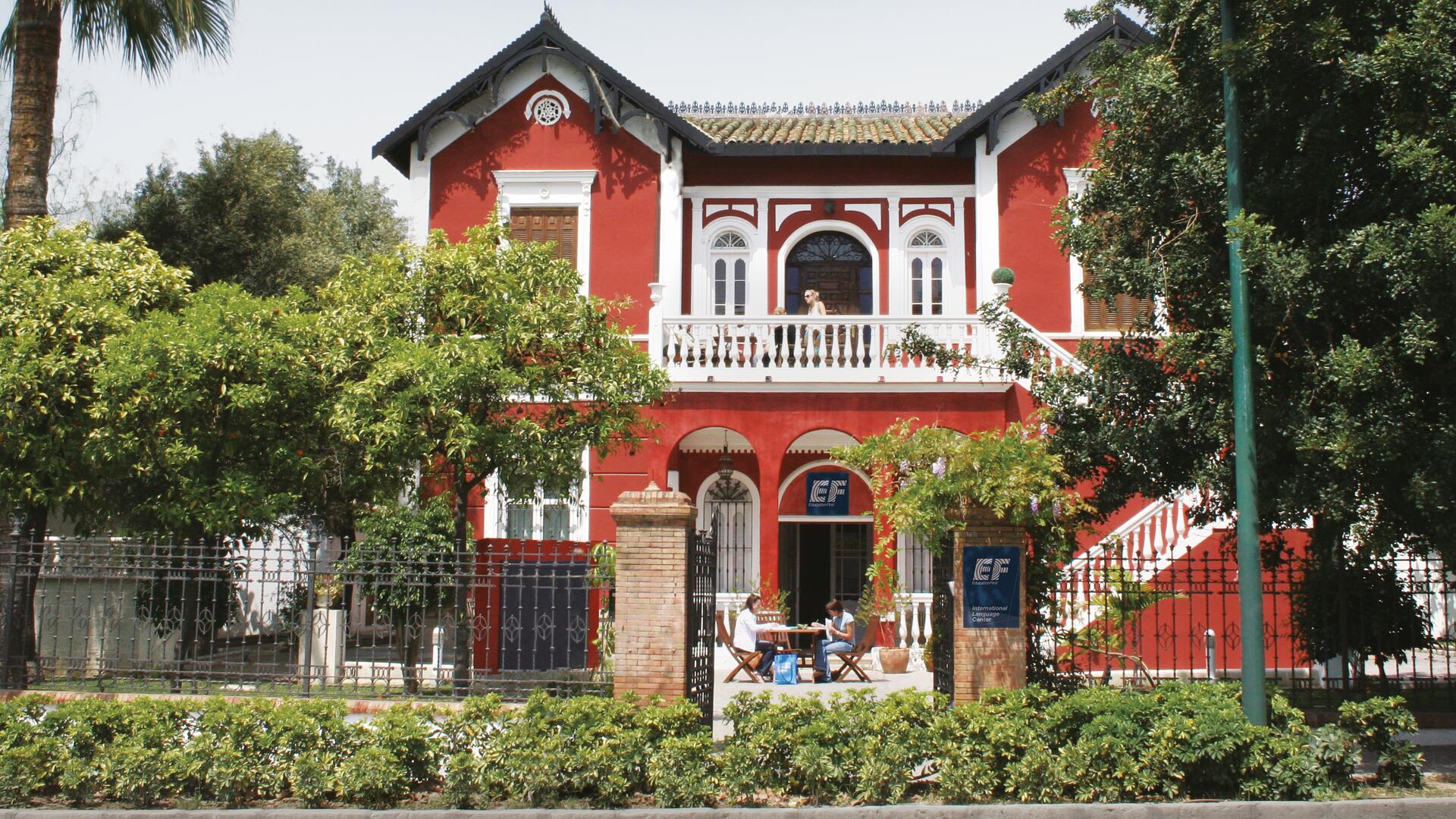 École EF à Séville: Villa rouge historique entourée de verdure.