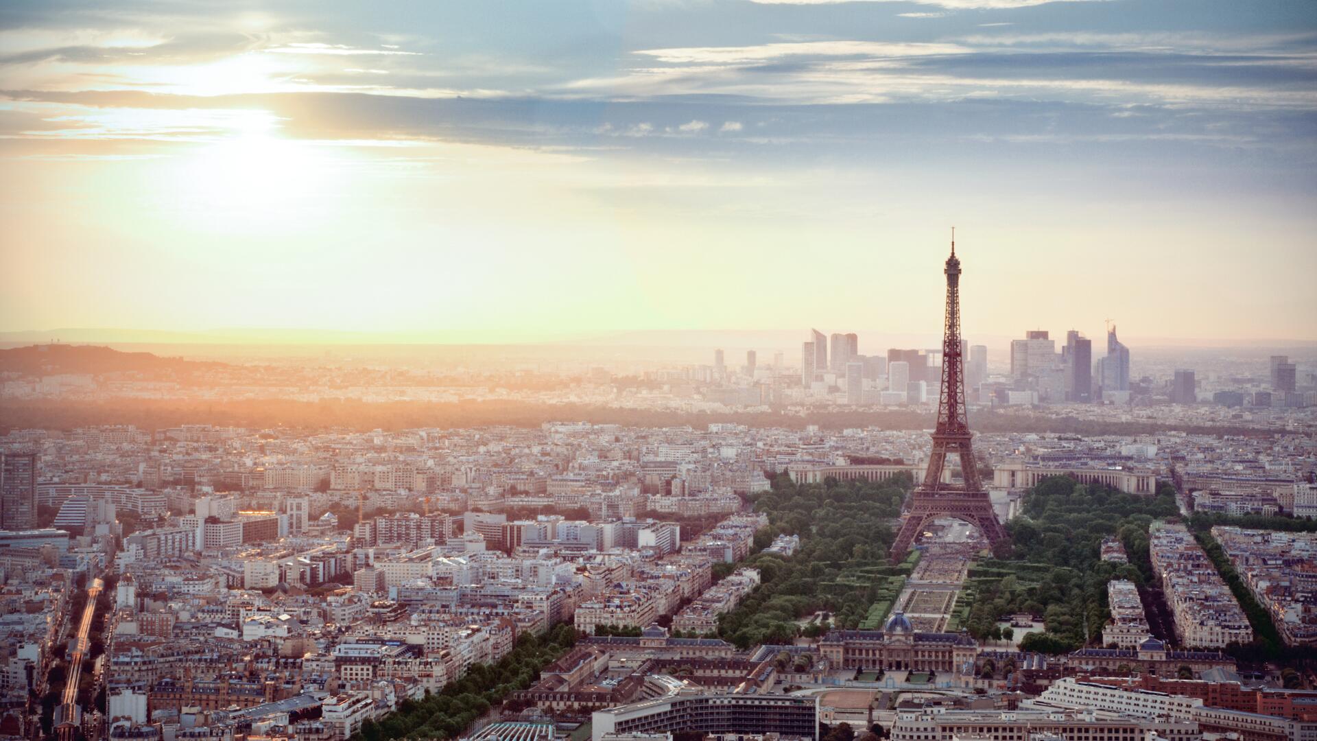 A picturesque view of Paris at sunset, featuring the Eiffel Tower prominently in the foreground with the city skyline in the background.