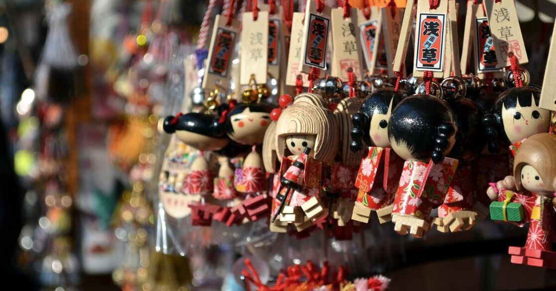 A close-up of many small Japanese Daruma dolls, sold as keychains. They come in various colors and designs.