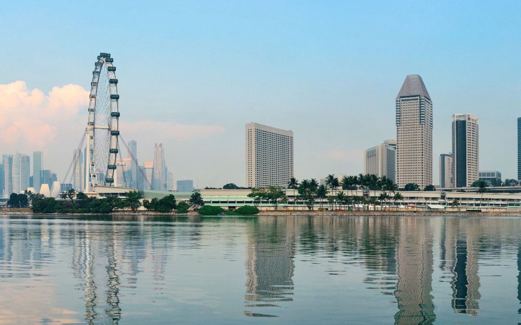 The image captures the Singapore skyline, featuring the Singapore Flyer observation wheel and modern skyscrapers reflected in the calm water.