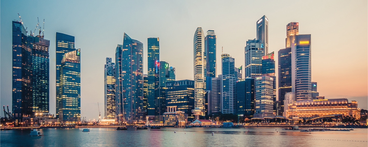 The Singapore skyline at dusk, featuring towering skyscrapers reflecting in the water, with city lights illuminating the urban landscape.