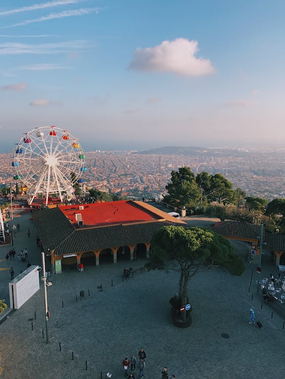A Ferris wheel and buildings with red roofs are visible on a hilltop overlooking a city.