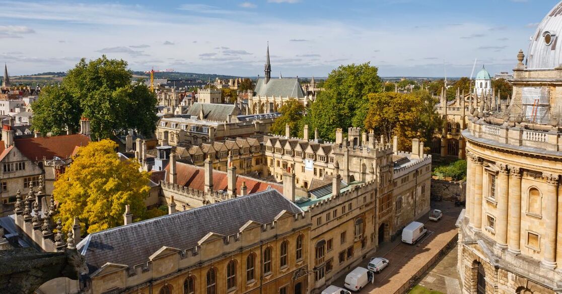 A picturesque view of Oxford, England, showcasing its iconic architecture, including the Radcliffe Camera and historic university buildings, adorned with autumn foliage.