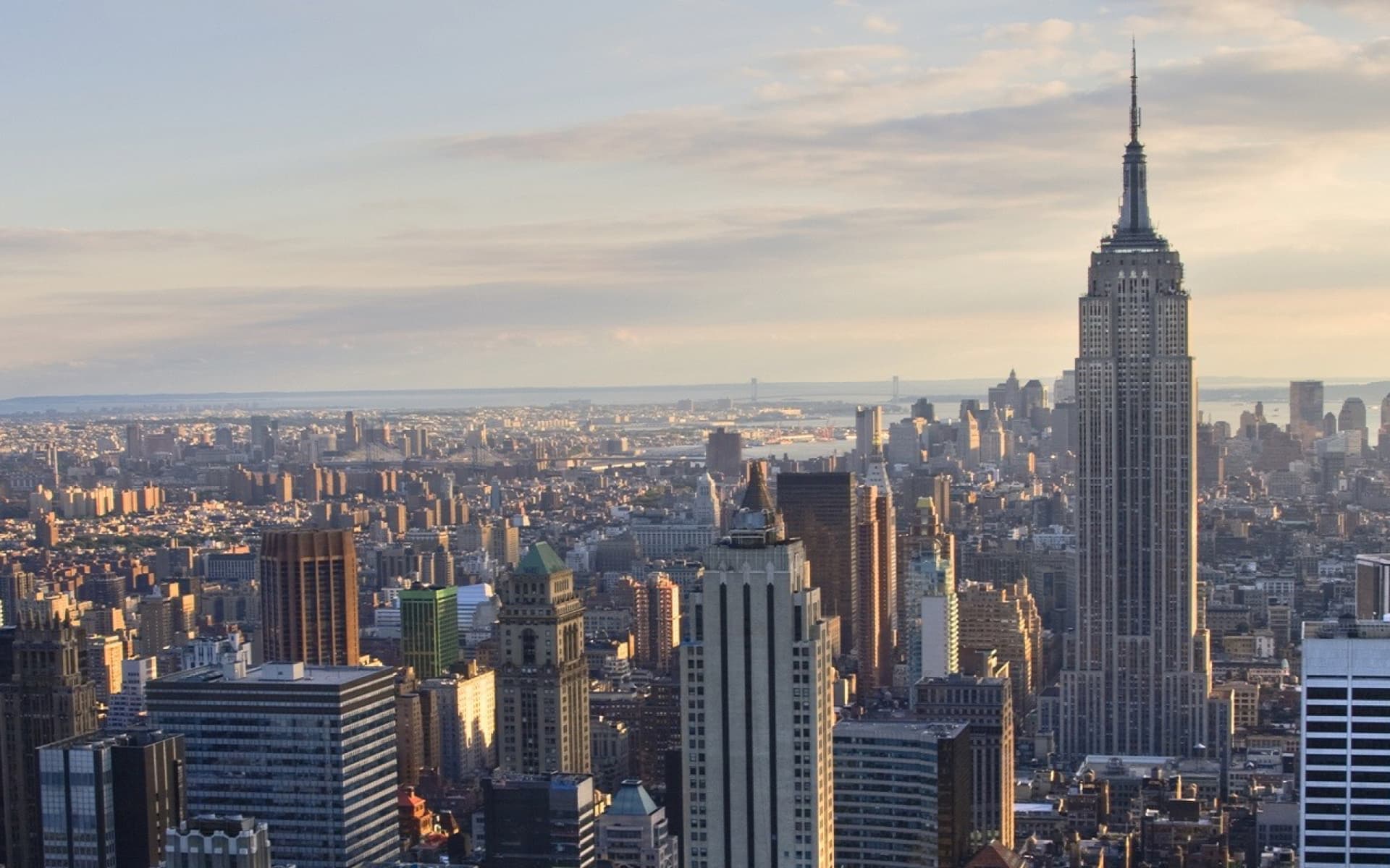 A breathtaking view of the New York City skyline at sunset, with the iconic Empire State Building prominently featured, majestically towering over the cityscape.